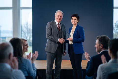 Award handshake on stage — News imagery, honours and prizes.
