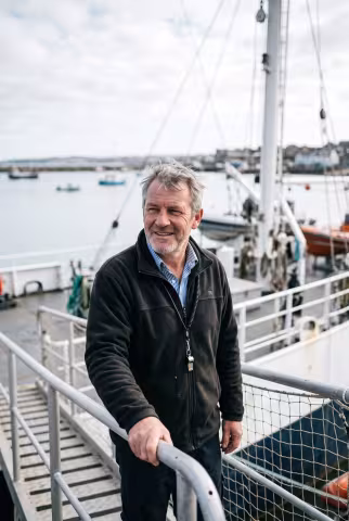 Marine operations lead portrait, research vessel gangway — Person `person_portrait`.